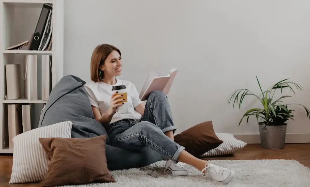 short-haired-girl-in-white-t-shirt-with-smile-reading-book-while-sitting-on-soft-bean-bag-1500x904